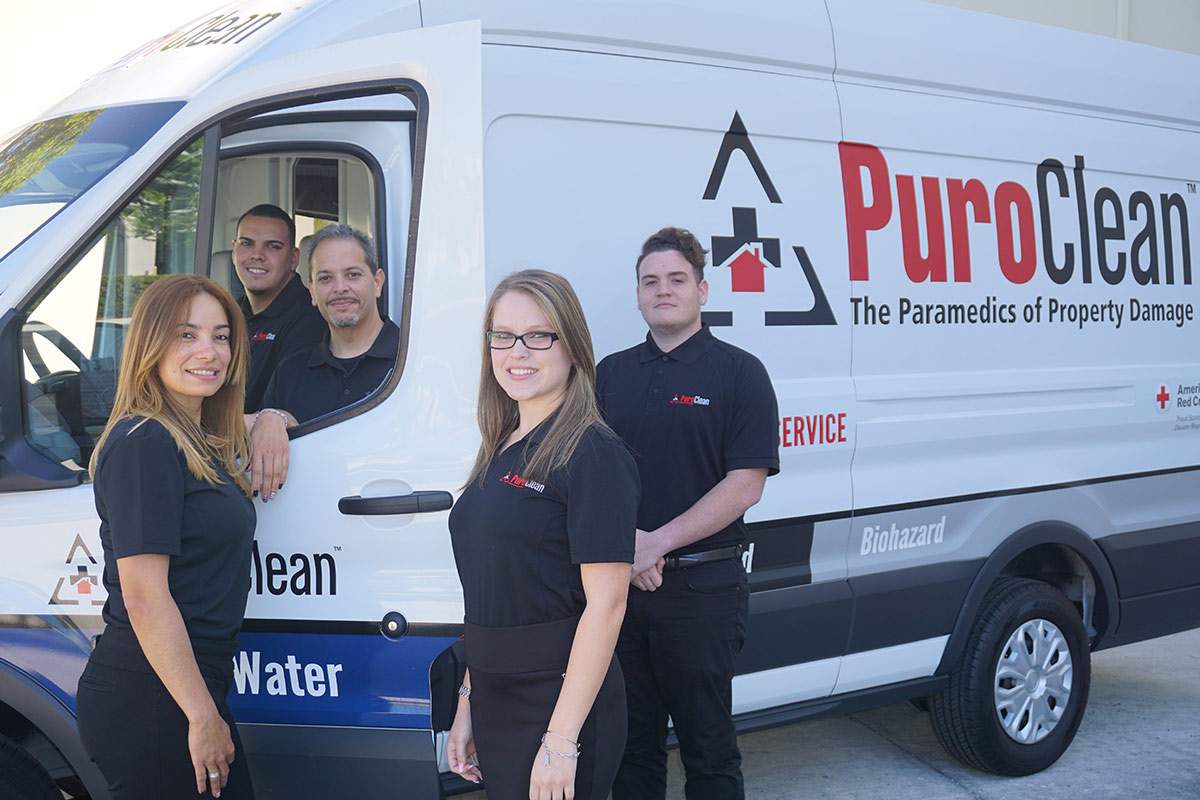 PuroClean team stands outside a PuroClean van
