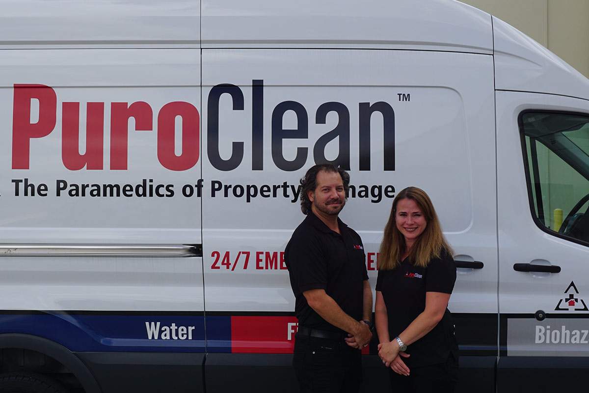 man and woman in front of a PuroClean van