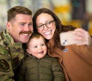 A veteran takes a photo with a woman and child