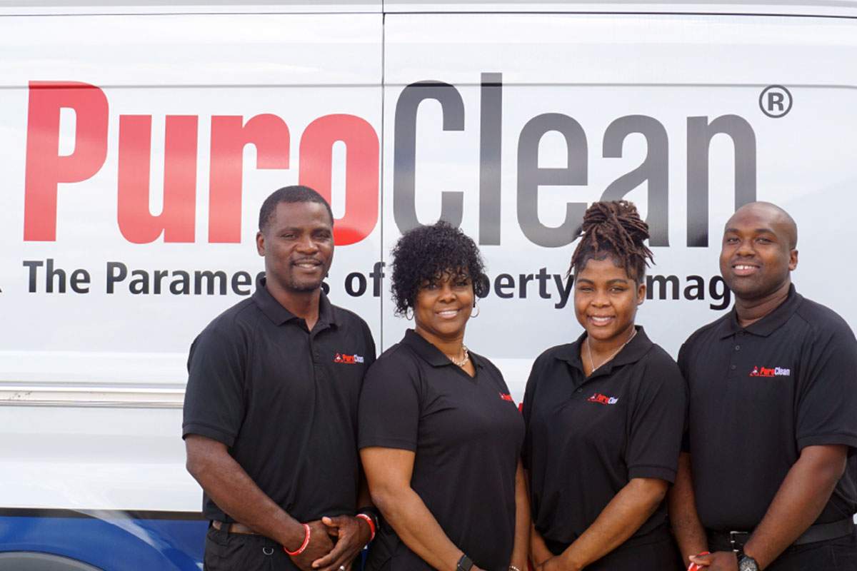 four PuroClean team members besides a of a company van