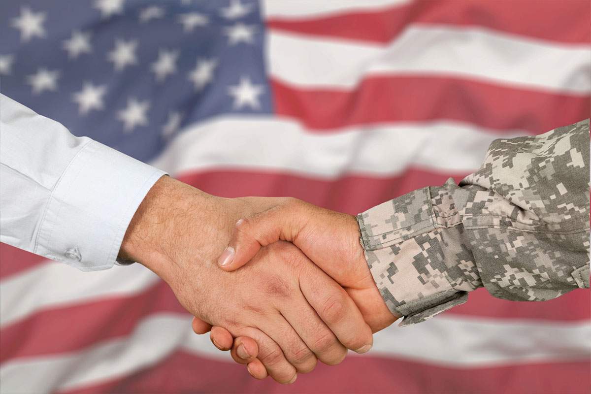 A business man and a veteran shake hands, as part of empowering veterans for business success