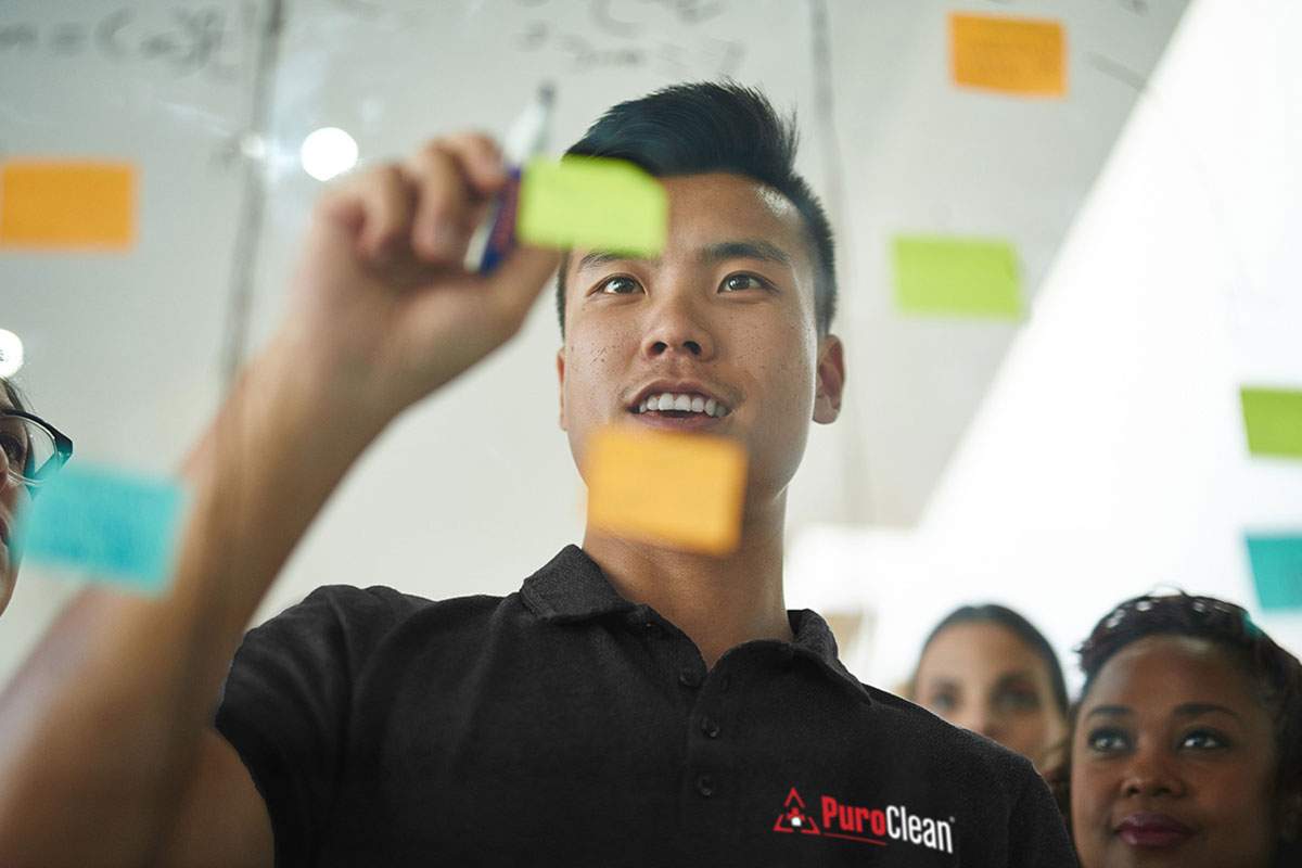 man writing on clear whiteboard