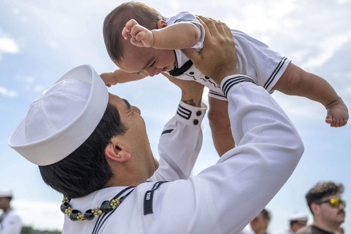 A naval officer bounces his baby overhead