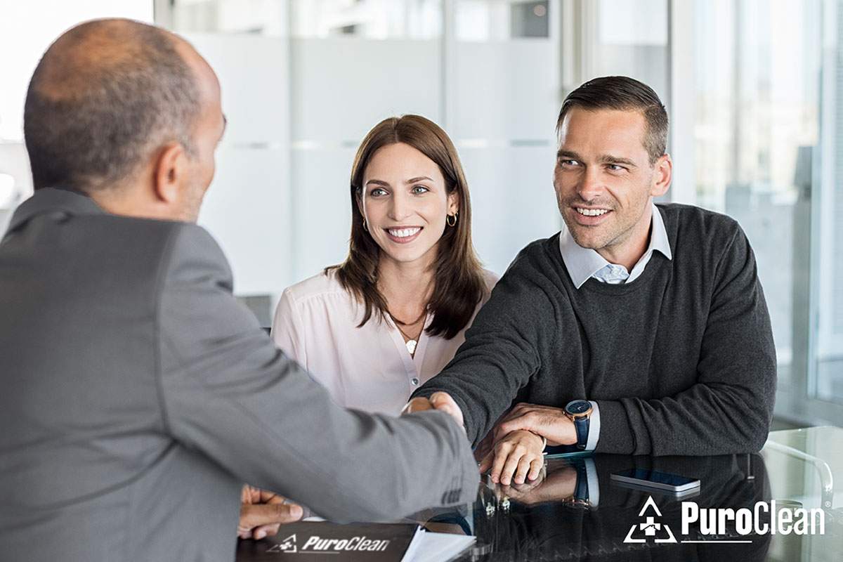 a couple shaking hands with a man
