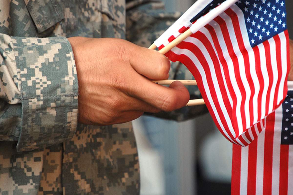 Military service member holds mini American flags