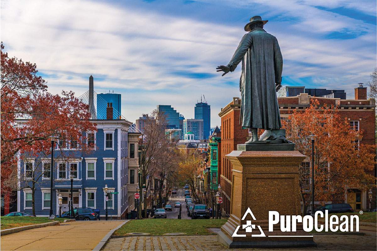 Statue of a man standing on a street corner, surrounded by urban scenery.