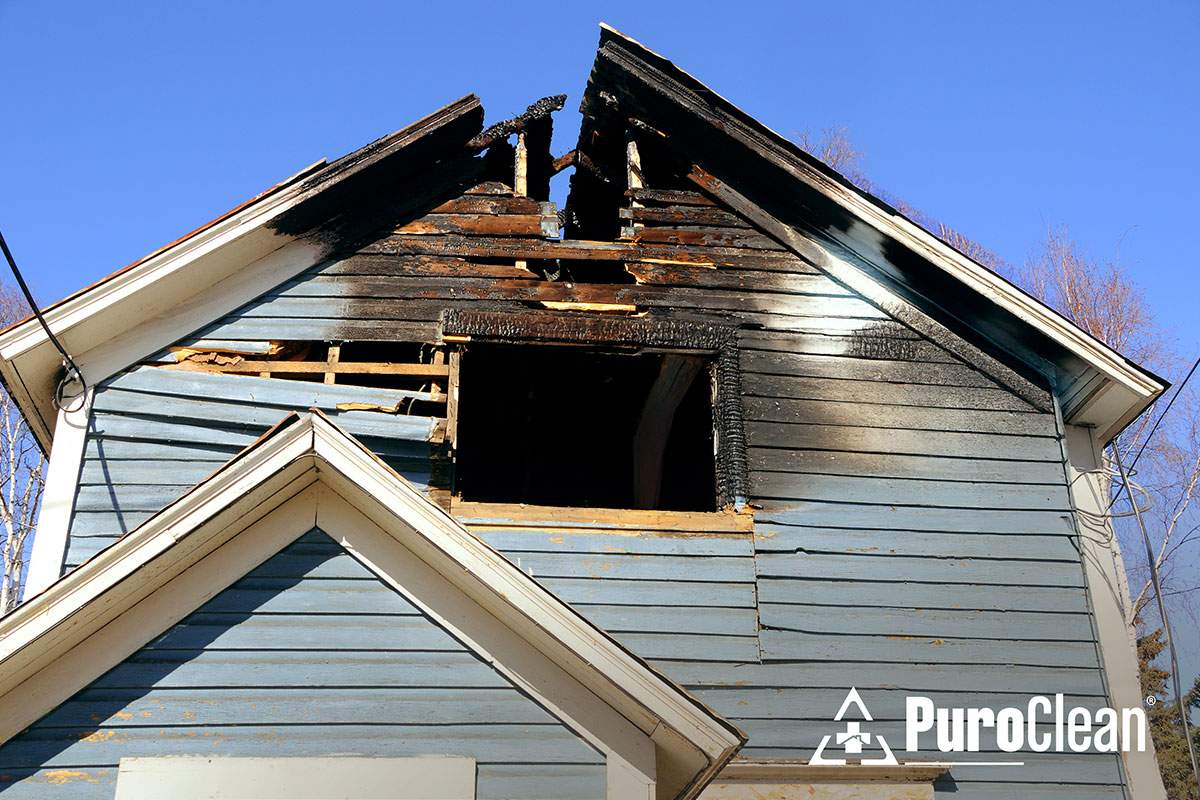 A house featuring a broken window and roof due to a fire.