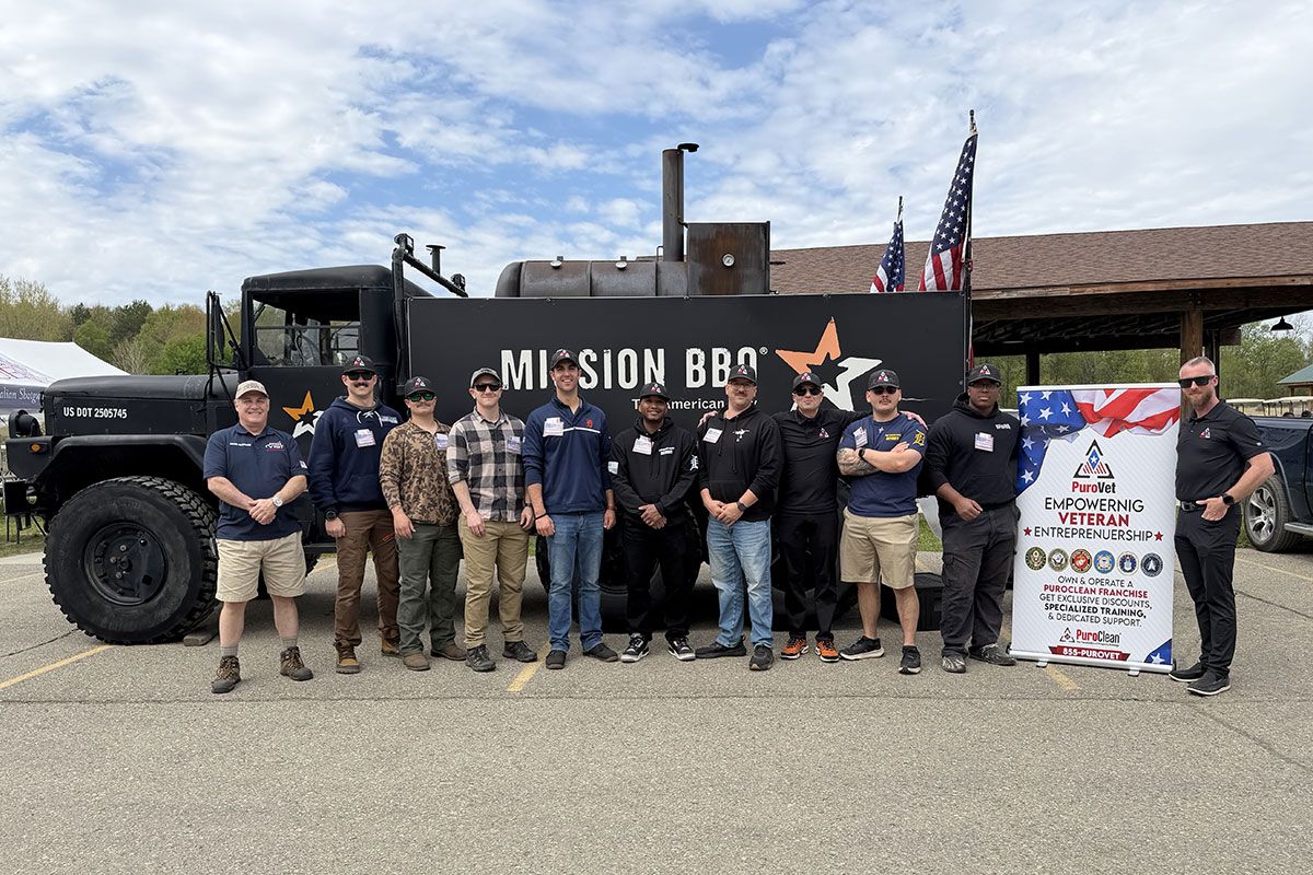 Sporting Clays event participants stand in front of a military vehicle